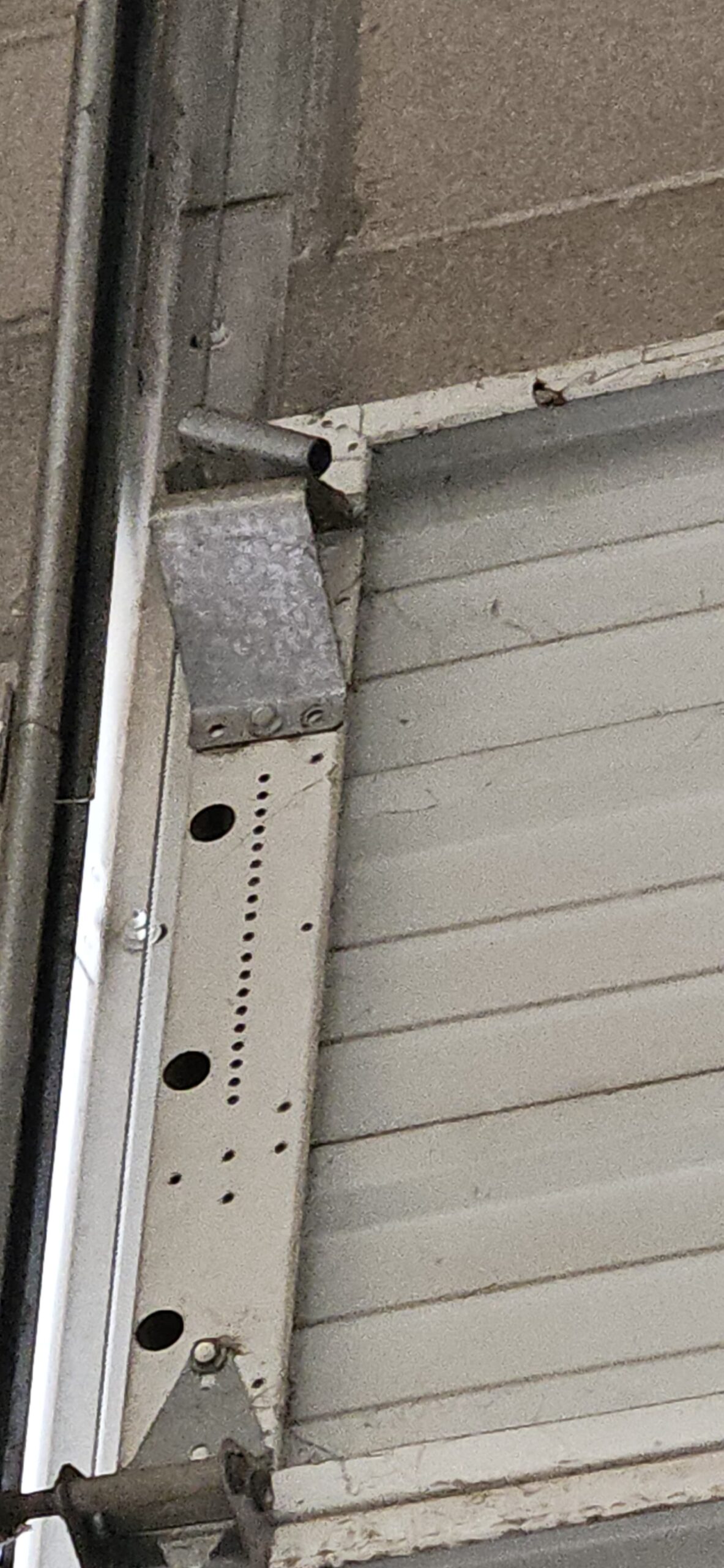 Bent upper roller bracket on a commercial garage door in Goodyear Arizona before repair