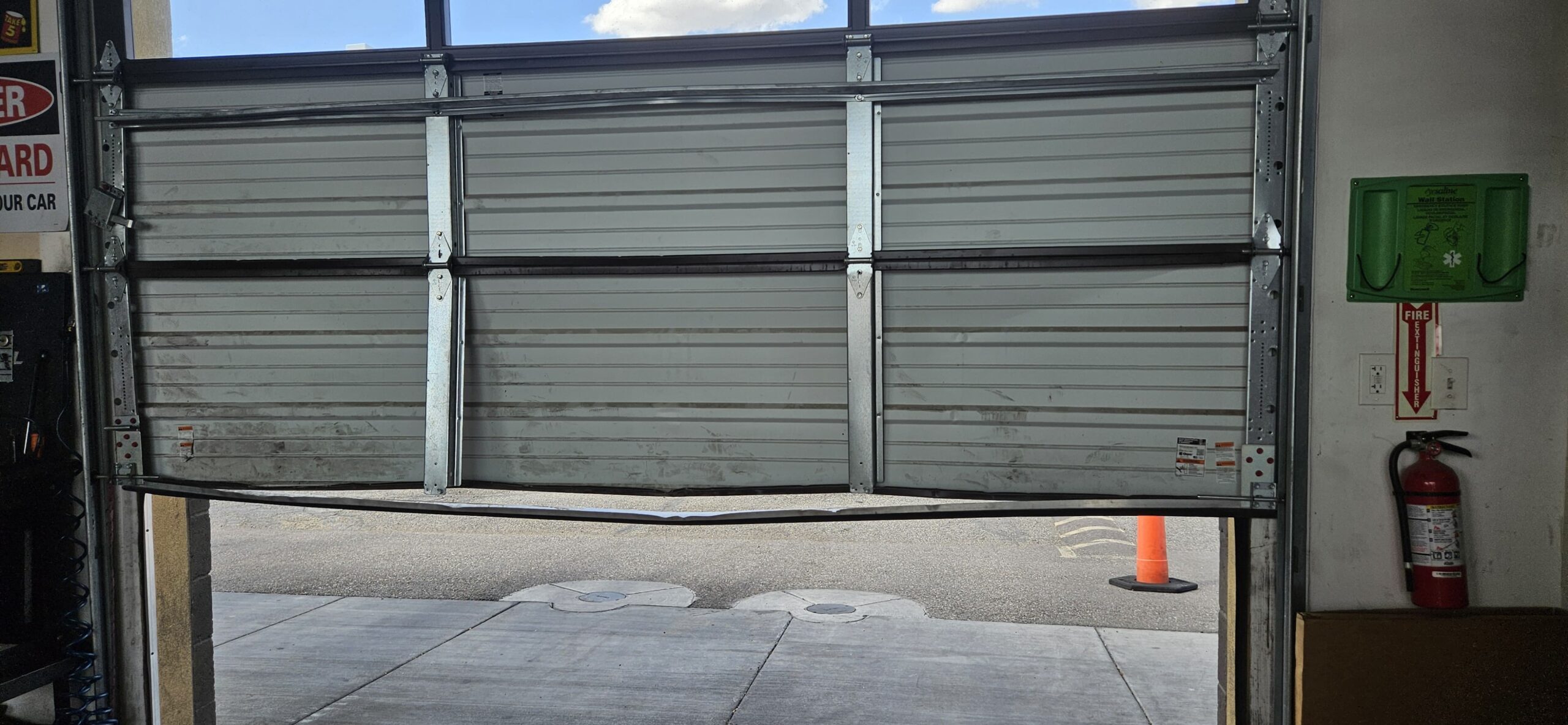 Damaged commercial garage door bottom panel at Take 5 Oil Change on W Bell Rd in Phoenix